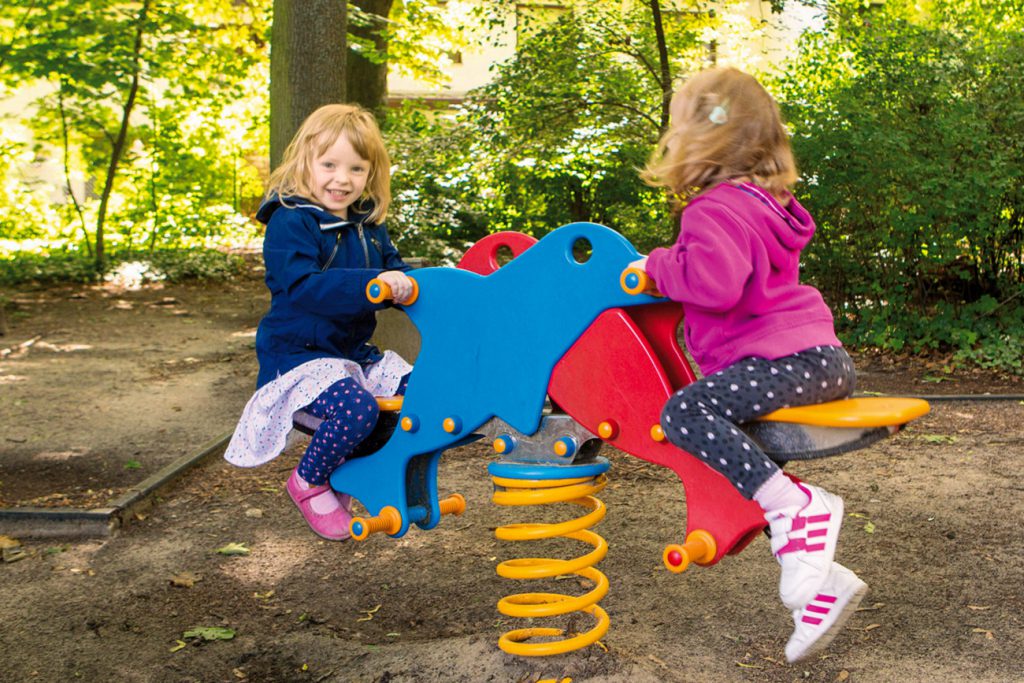 Zwei kleine Mädchen auf Schaukelpferden